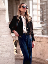 a lady wears a black v-neck crop jacket with jeans